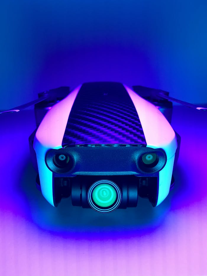 A sleek white drone illuminated by vibrant blue and purple neon lights, showcasing modern technology.