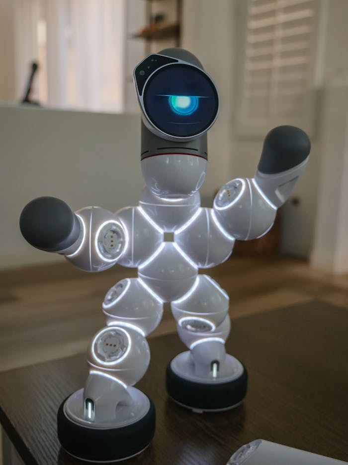 Modern walking robot with LED lights standing on a wooden surface indoors. Shallow focus emphasizes its futuristic design.